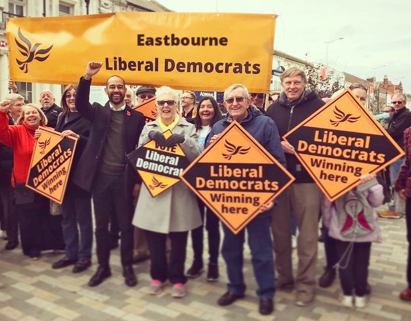 Josh Babarinde MP with Eastbourne Liberal Democrat supporters under the party banner in the town centre